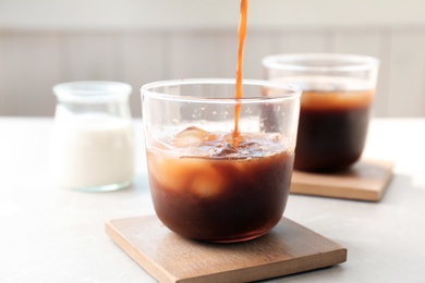 Pouring cold brew coffee into glass on table