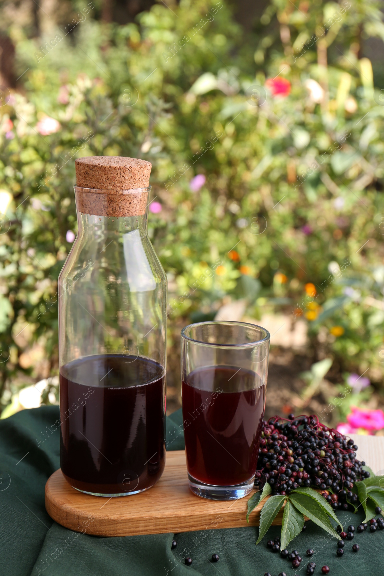 Photo of Elderberry drink and Sambucus berries on table outdoors