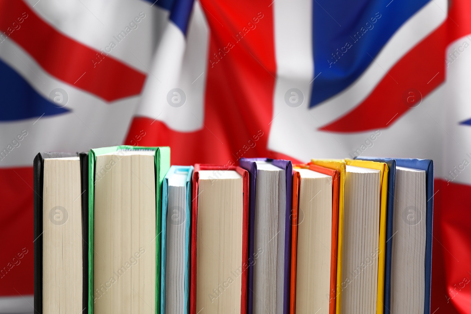 Photo of Learning foreign language. Different books against flag of United Kingdom, closeup