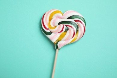 Photo of Stick with heart shaped lollipop on turquoise background, top view