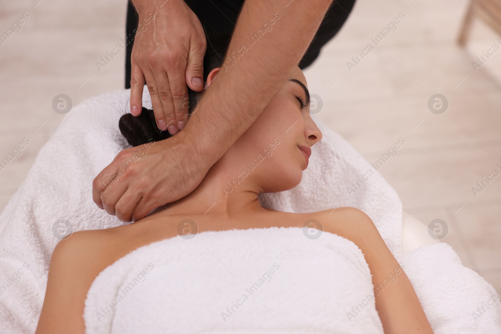 Photo of Woman receiving professional neck massage on couch indoors