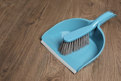 Photo of Plastic whisk broom with dustpan on wooden floor