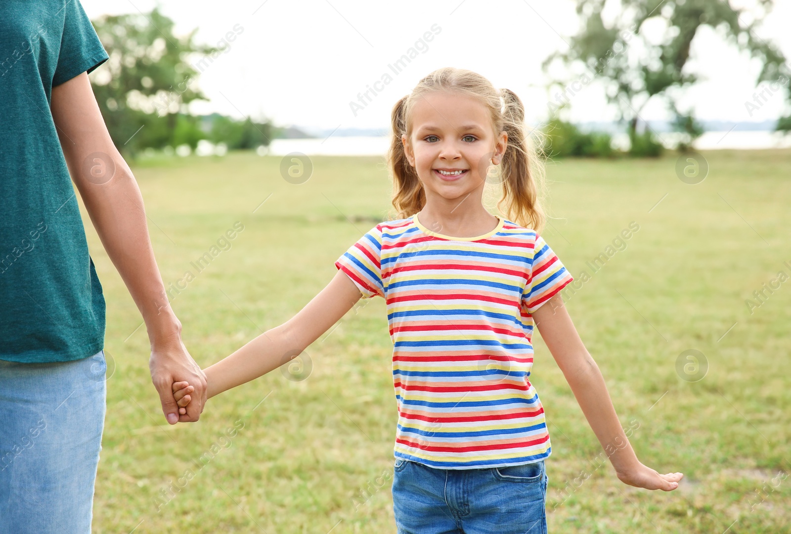 Photo of Woman holding hands with her child outdoors. Happy family