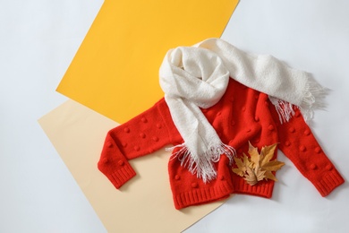 Flat lay composition with cozy knitted sweater on color background. Space for text