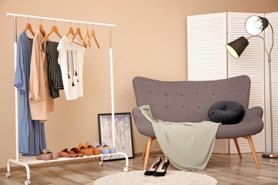 Photo of Wardrobe rack with female clothes in stylish dressing room