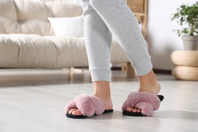 Photo of Woman wearing soft slippers at home, closeup of legs