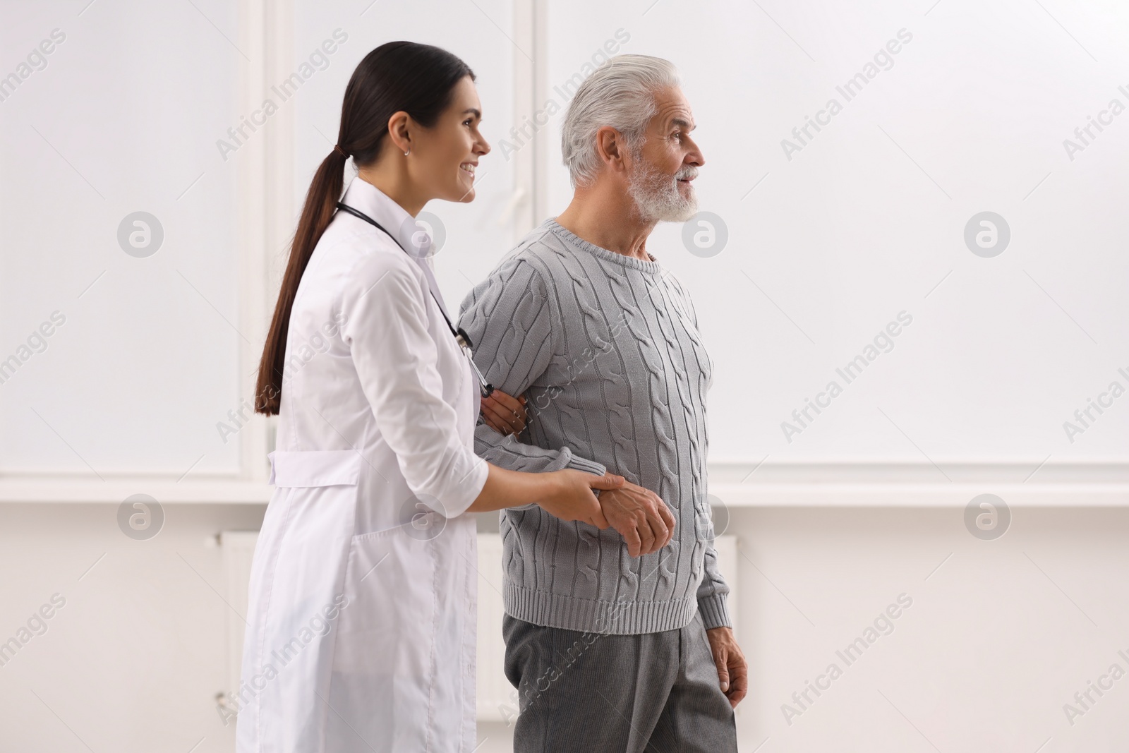 Photo of Smiling nurse supporting elderly patient in hospital
