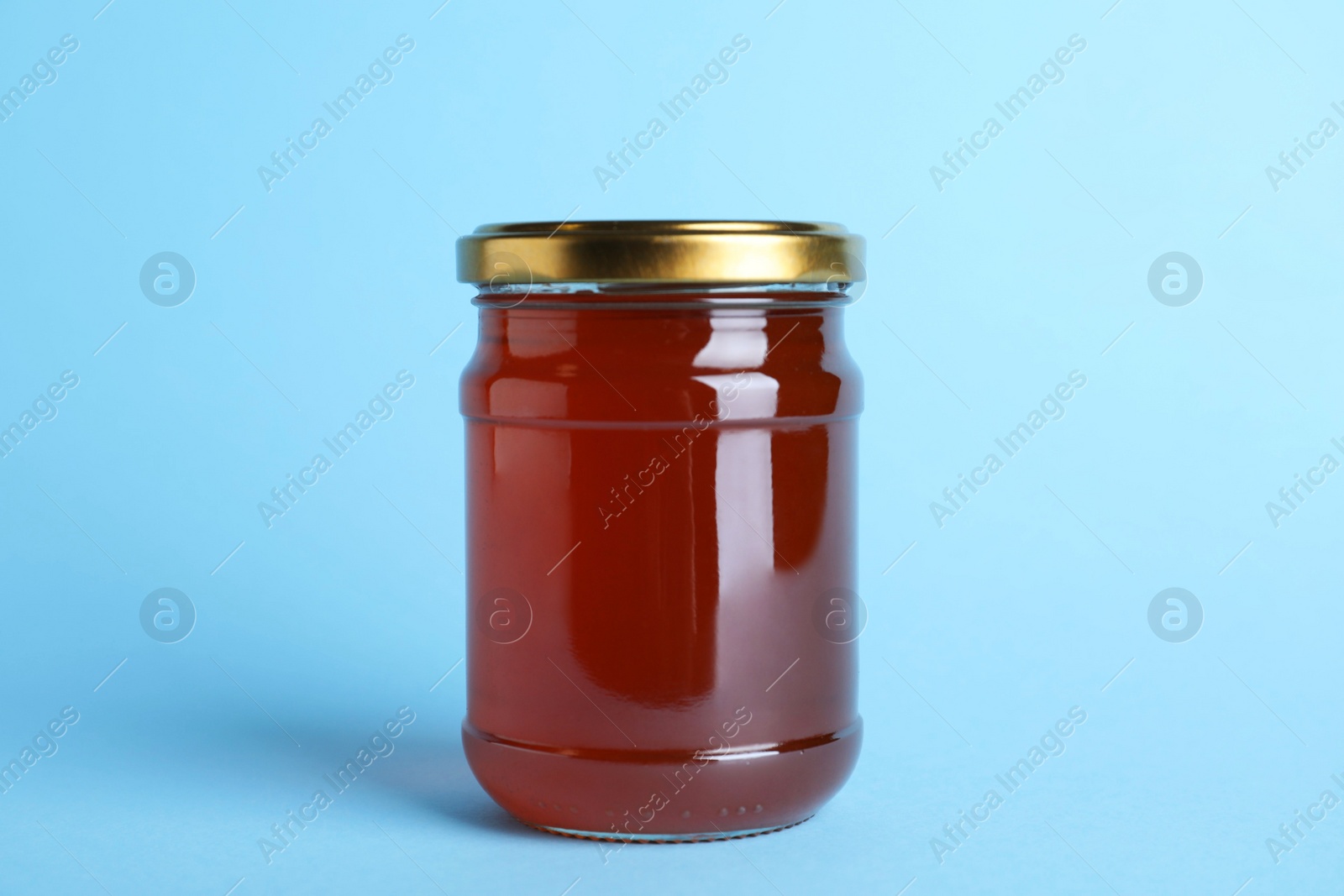 Photo of Jar of organic honey on light blue background