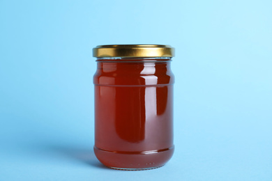 Jar of organic honey on light blue background