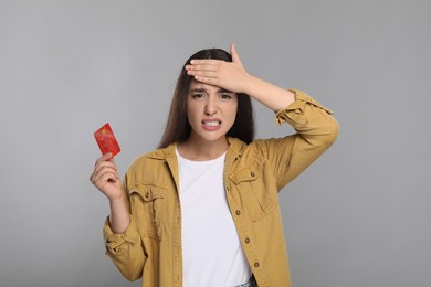 Photo of Worried woman with credit card on light gray background. Debt problem