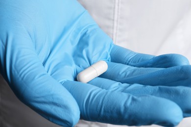 Photo of Doctor in medical glove holding pill, closeup view