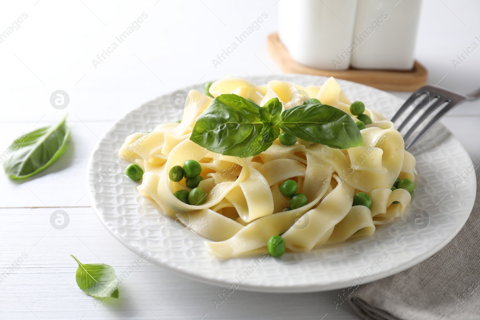 Photo of Delicious pasta with green peas served on white wooden table