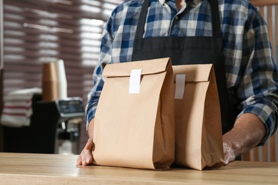 Photo of Worker with paper bags at counter in cafe, closeup