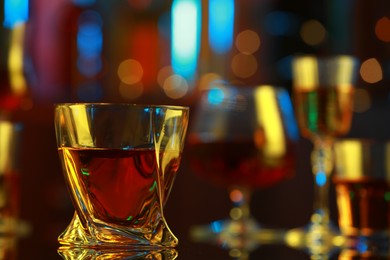 Photo of One liqueur in glass on mirror table against blurred background, closeup. Space for text