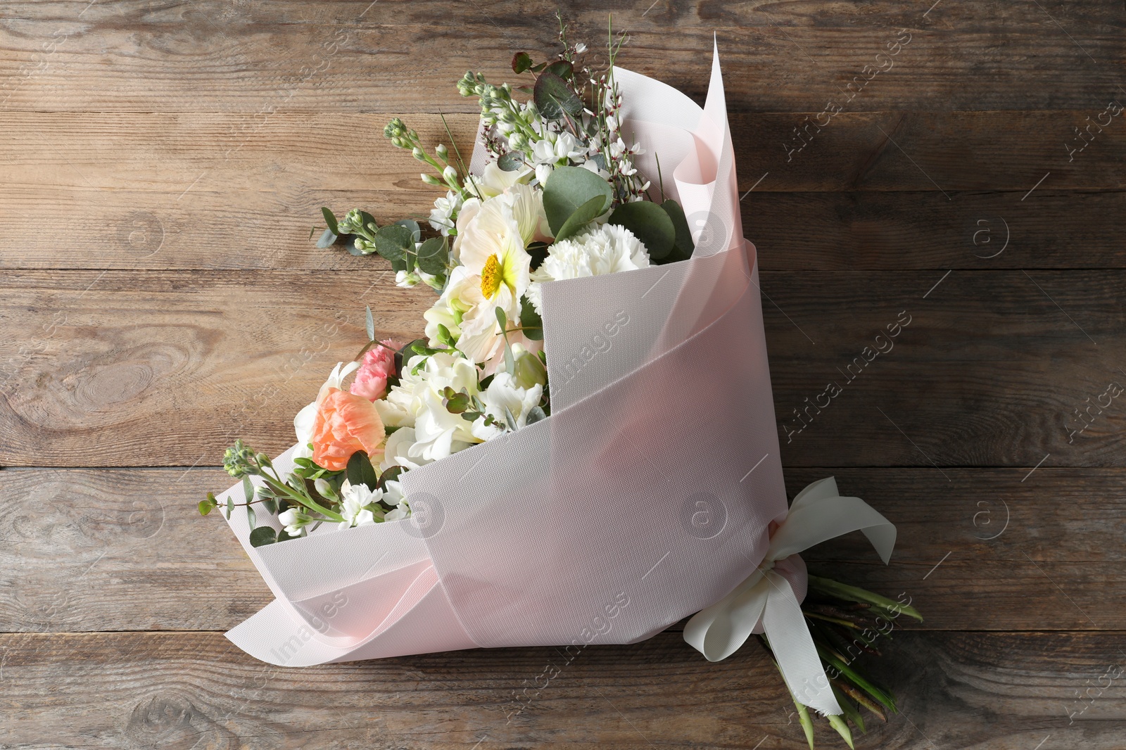 Photo of Bouquet of beautiful flowers on wooden table, top view