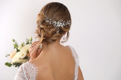 Photo of Young bride with elegant hairstyle holding wedding bouquet on white background, back view