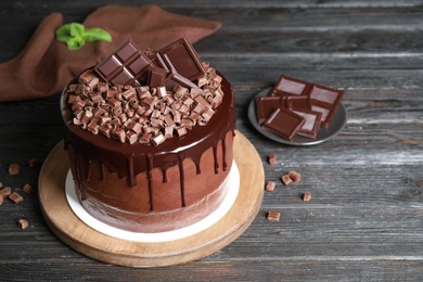 Photo of Freshly made delicious chocolate cake on black wooden table. Space for text