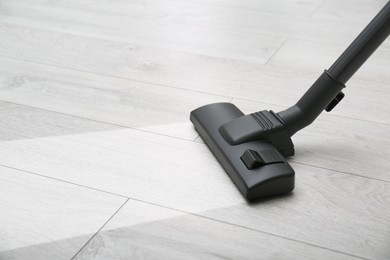 Vacuuming dirty white wooden floor. Clean area after using device, closeup