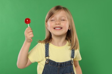 Photo of Portrait of happy girl with lollipop on green background