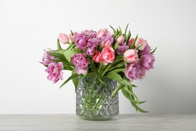 Photo of Beautiful bouquet of colorful tulip flowers on wooden table