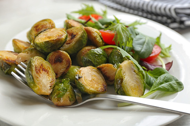 Photo of Delicious roasted brussels sprouts with different vegetables on plate, closeup