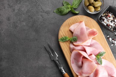 Photo of Tasty ham with basil, olives and spices served on grey table, flat lay. Space for text