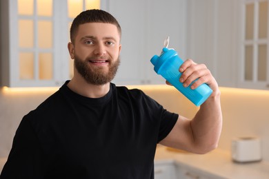 Young man with shaker of protein in kitchen