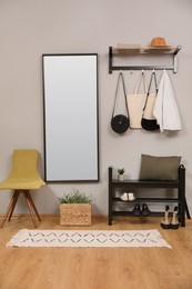 Photo of Modern hallway interior with stylish chair, shoe rack and mirror