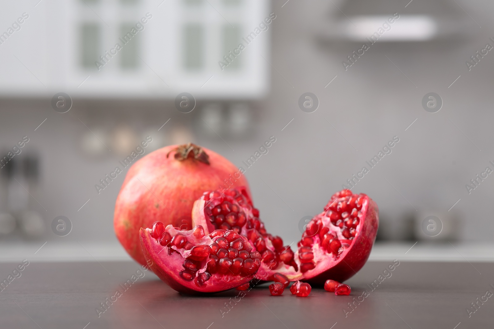 Photo of Whole and cut pomegranates on wooden counter in kitchen