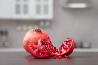 Photo of Whole and cut pomegranates on wooden counter in kitchen