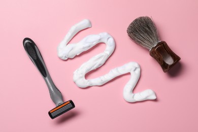 Photo of Sample of shaving foam, brush and razor on pink background, flat lay