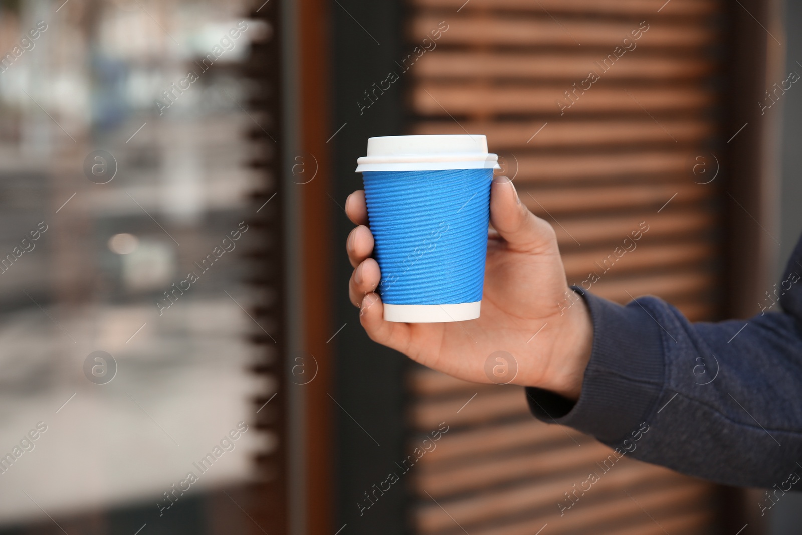 Photo of Man with takeaway coffee cup outdoors, closeup