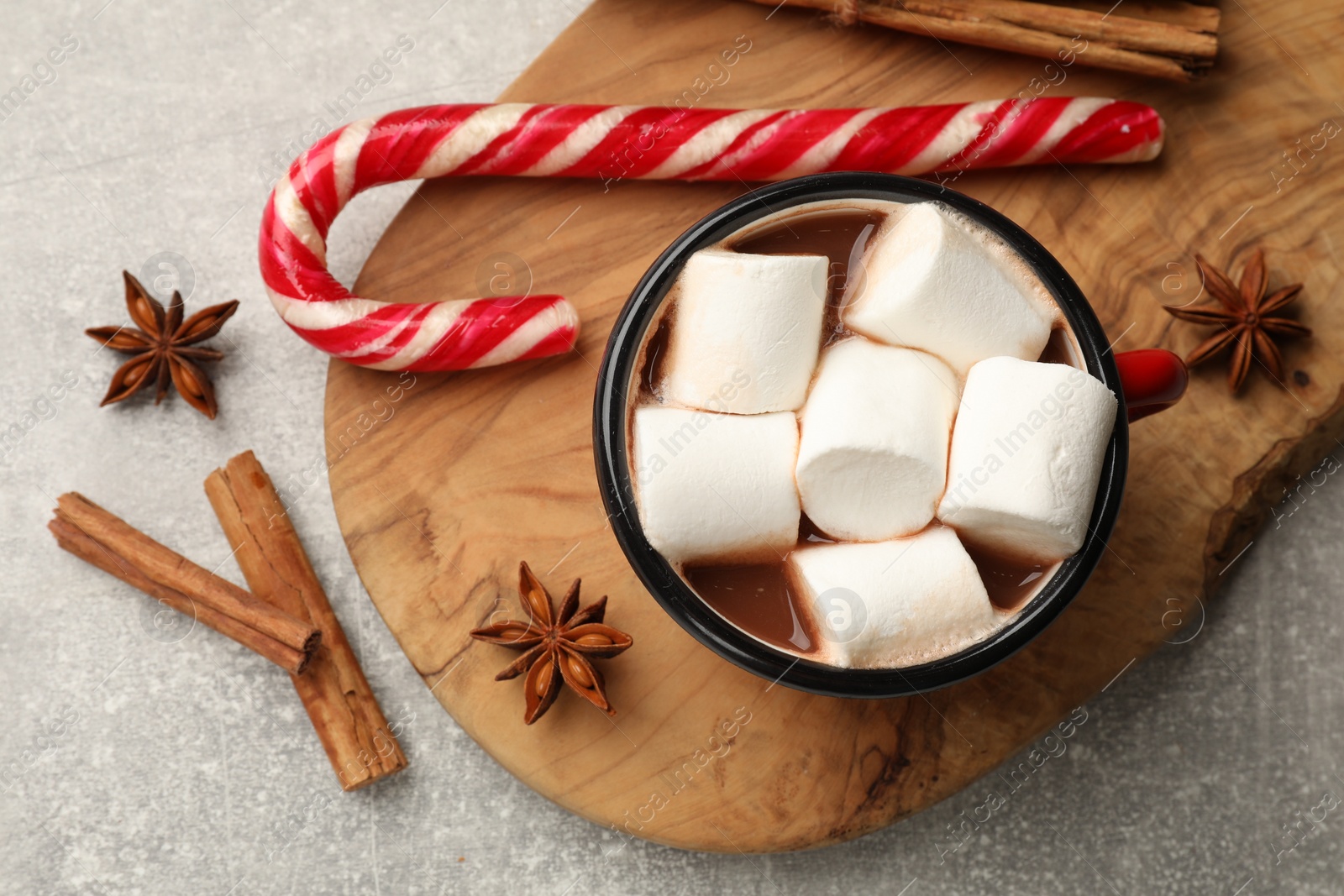 Photo of Tasty hot chocolate with marshmallows, candy cane and spices on light grey table, flat lay