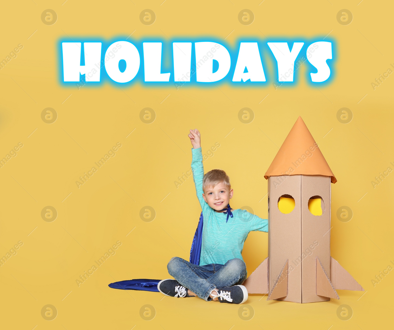 Image of School holidays. Cute little child playing with cardboard rocket near yellow wall