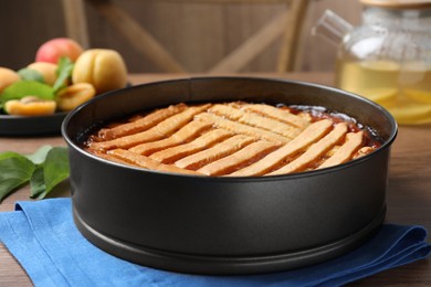 Delicious apricot pie in baking dish on wooden table, closeup