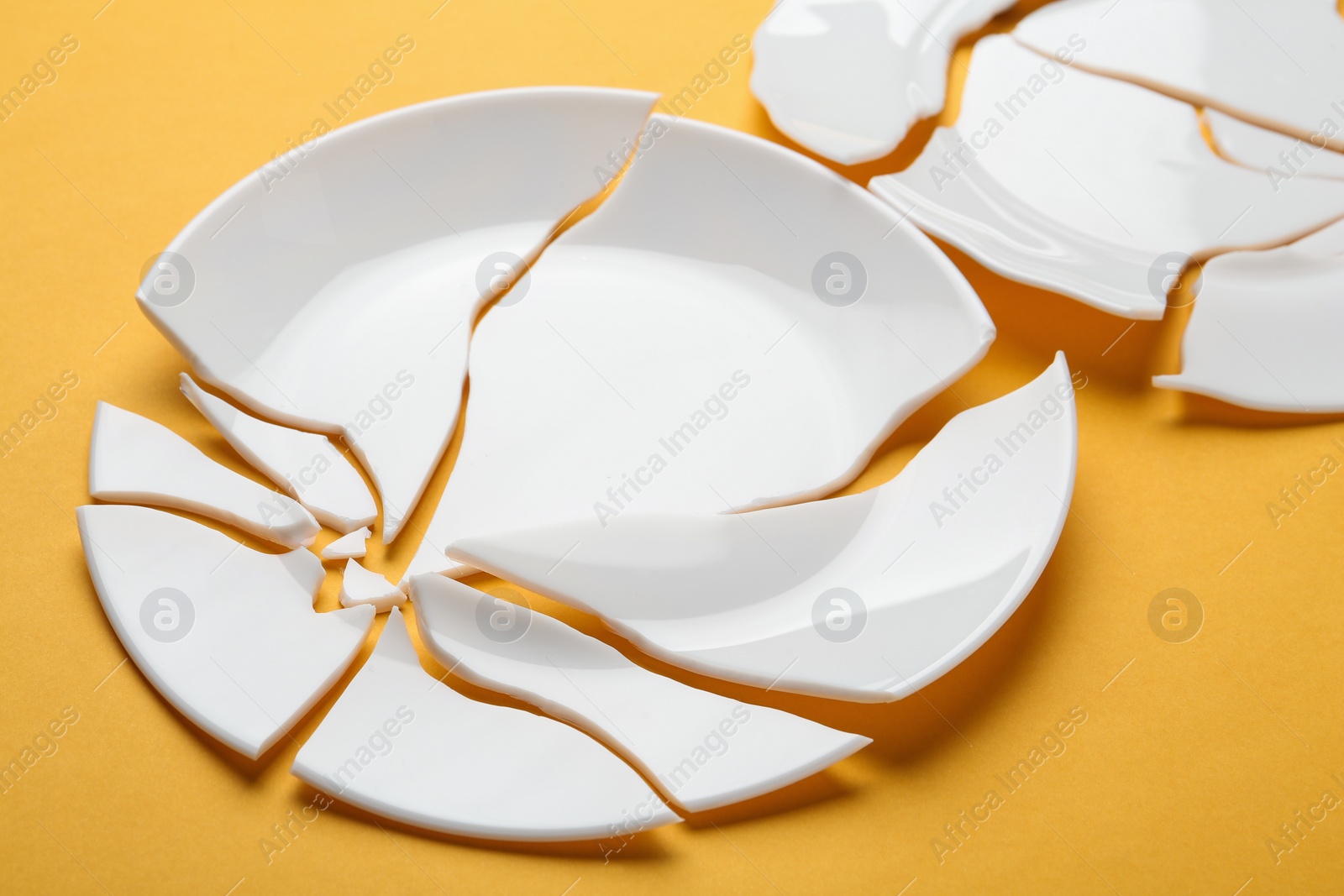 Photo of Two broken ceramic plates on orange background, closeup