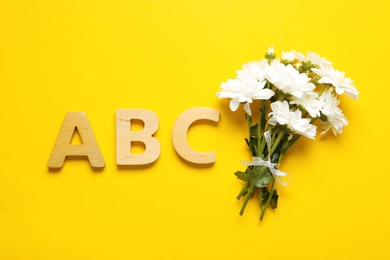 Photo of Flat lay composition with flowers and letters on yellow background. Teacher's day