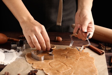 Woman making Christmas cookies at wooden table, closeup