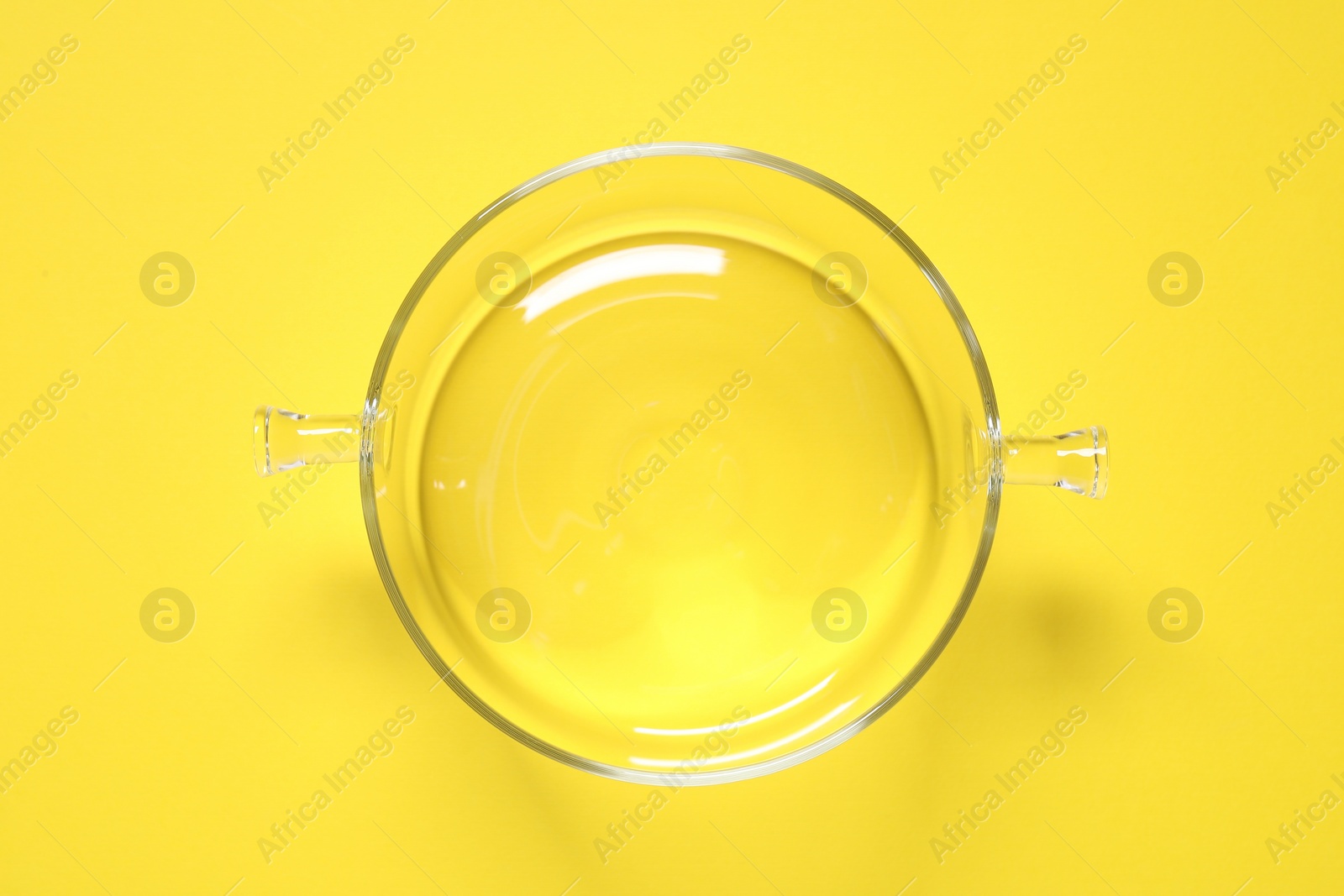 Photo of Empty glass pot on yellow background, top view