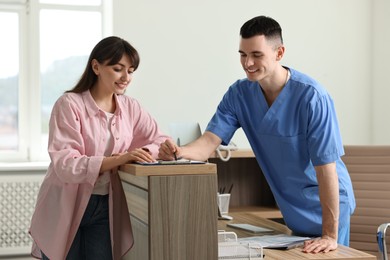 Photo of Smiling medical assistant working with patient at hospital reception