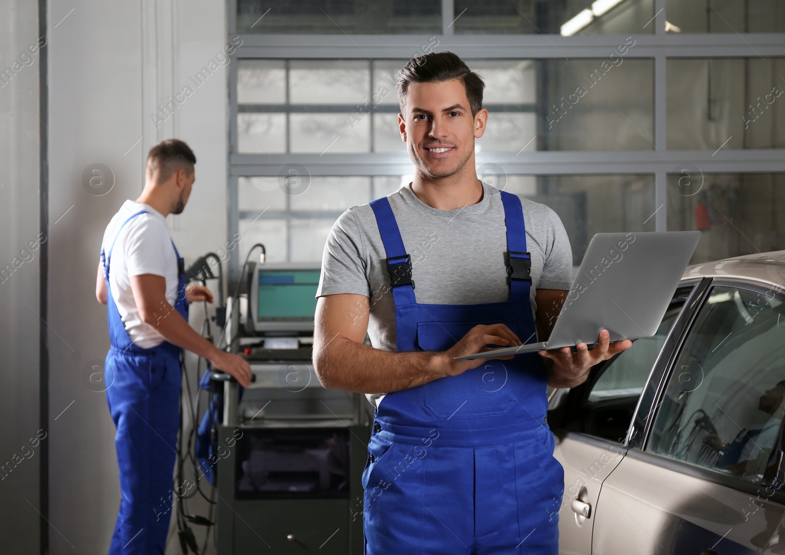 Photo of Mechanic with laptop doing car diagnostic at automobile repair shop