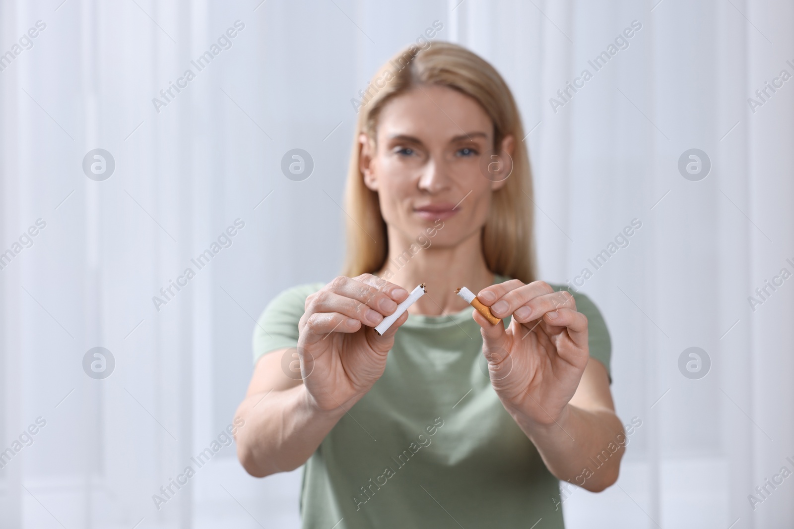 Photo of Woman with broken cigarette on light background, selective focus. Quitting smoking concept