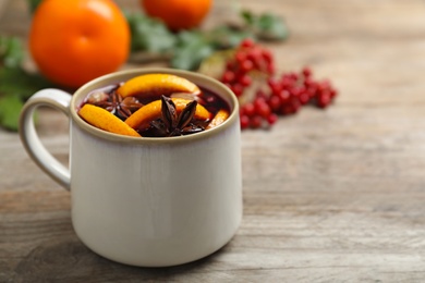 Photo of Cup with tasty mulled wine on wooden table