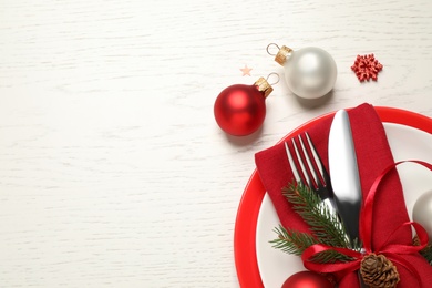 Festive table setting with beautiful dishware and Christmas decor on white wooden background, flat lay. Space for text