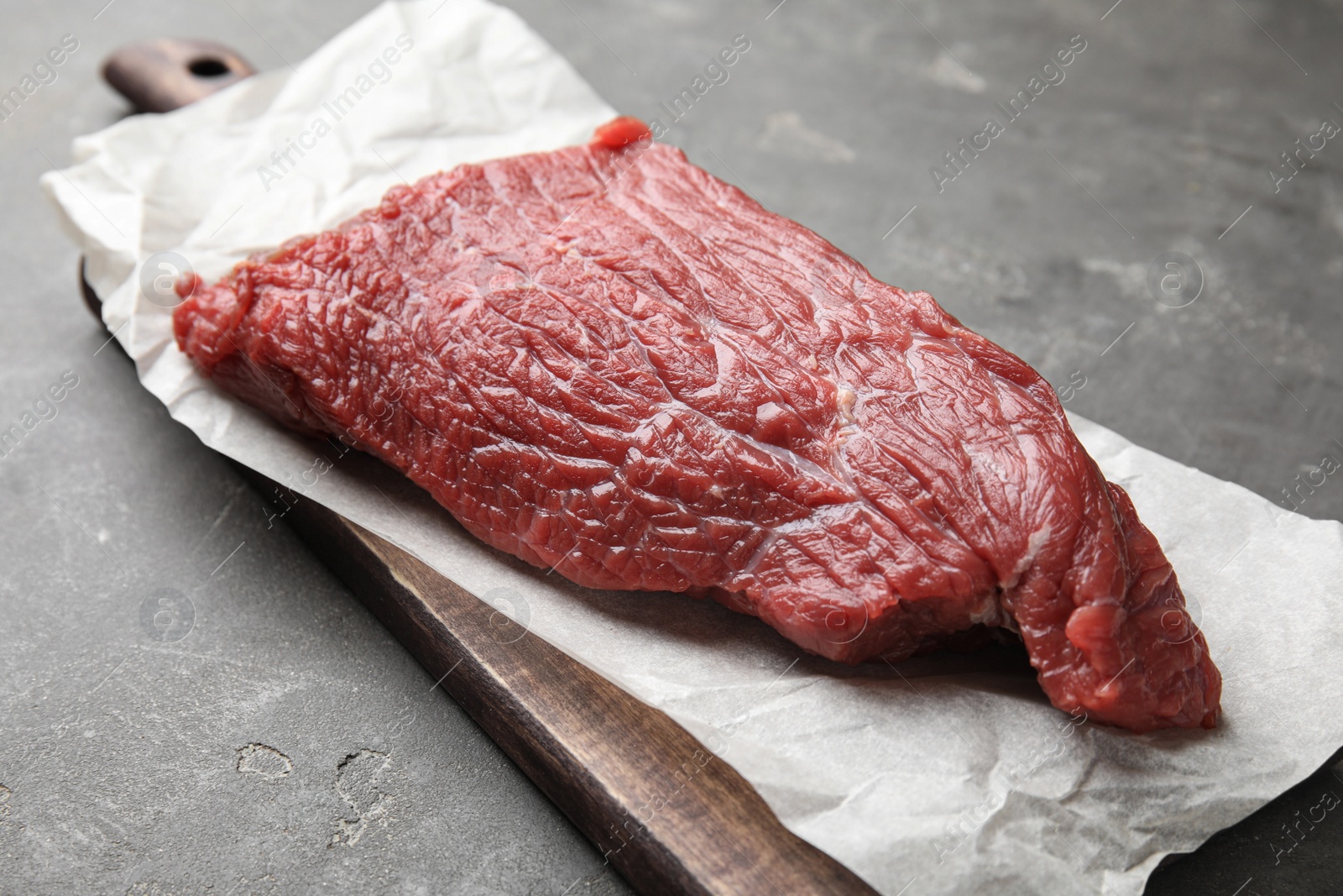Photo of Fresh raw beef cut on grey table, closeup