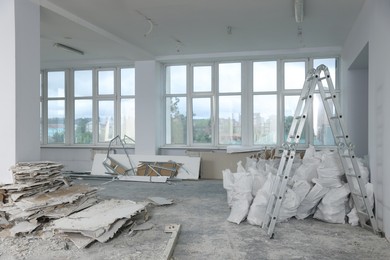 Photo of Used building materials and stepladder in room prepared for renovation