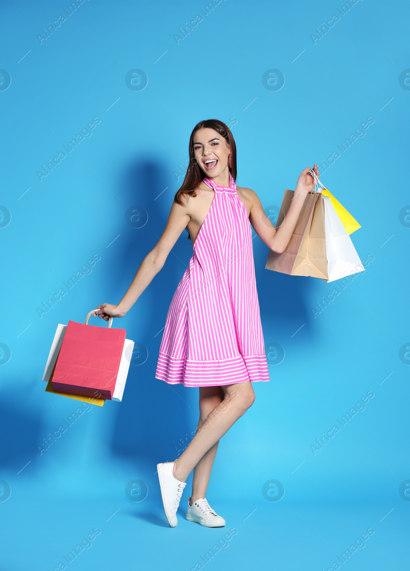 Photo of Young woman with shopping bags on color background