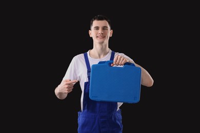 Professional repairman with tool box on black background