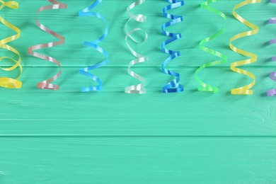 Photo of Colorful serpentine streamers on turquoise wooden background. Space for text