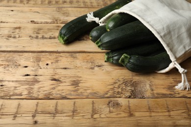 Photo of Sack with green ripe zucchinis on wooden table. Space for text